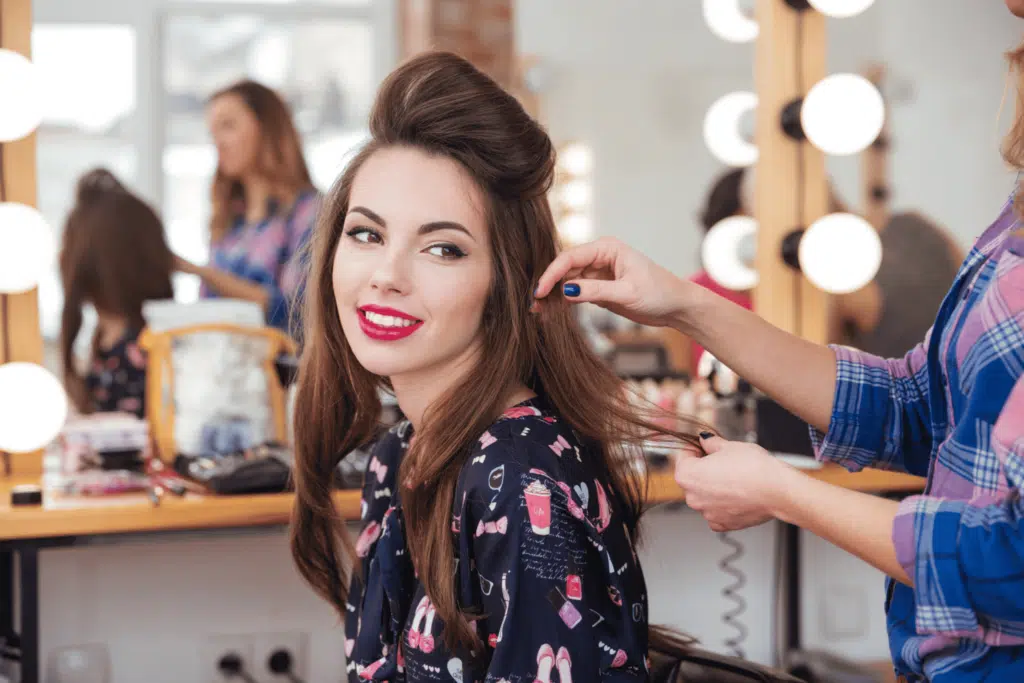 Female hairdresser making hairstyle to  woman in beauty salon