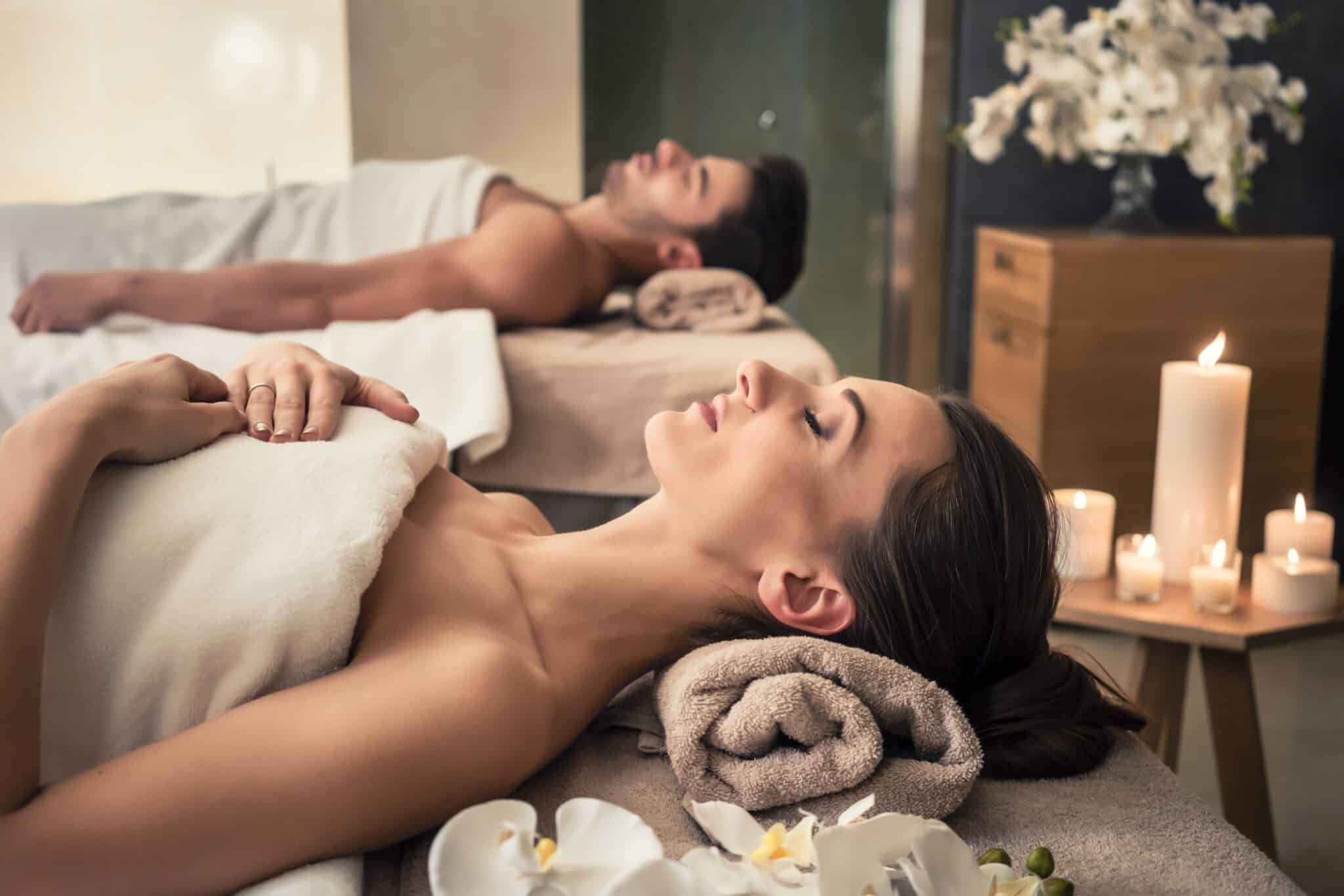 Couple in wellness center relaxing lying down with towels.