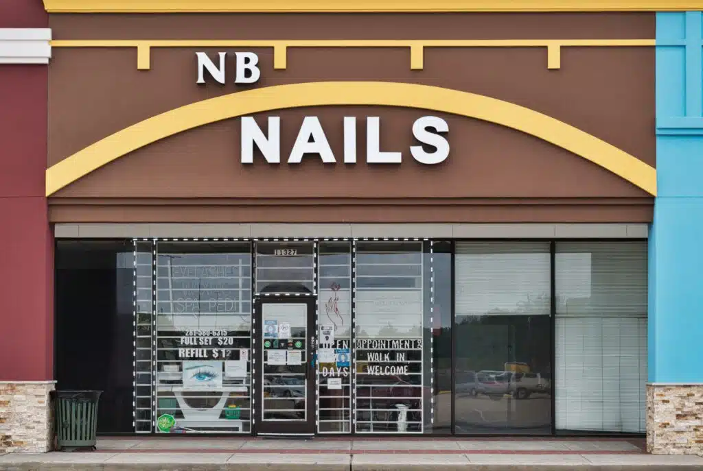 front of a nail salon business with glass door and brown façade 