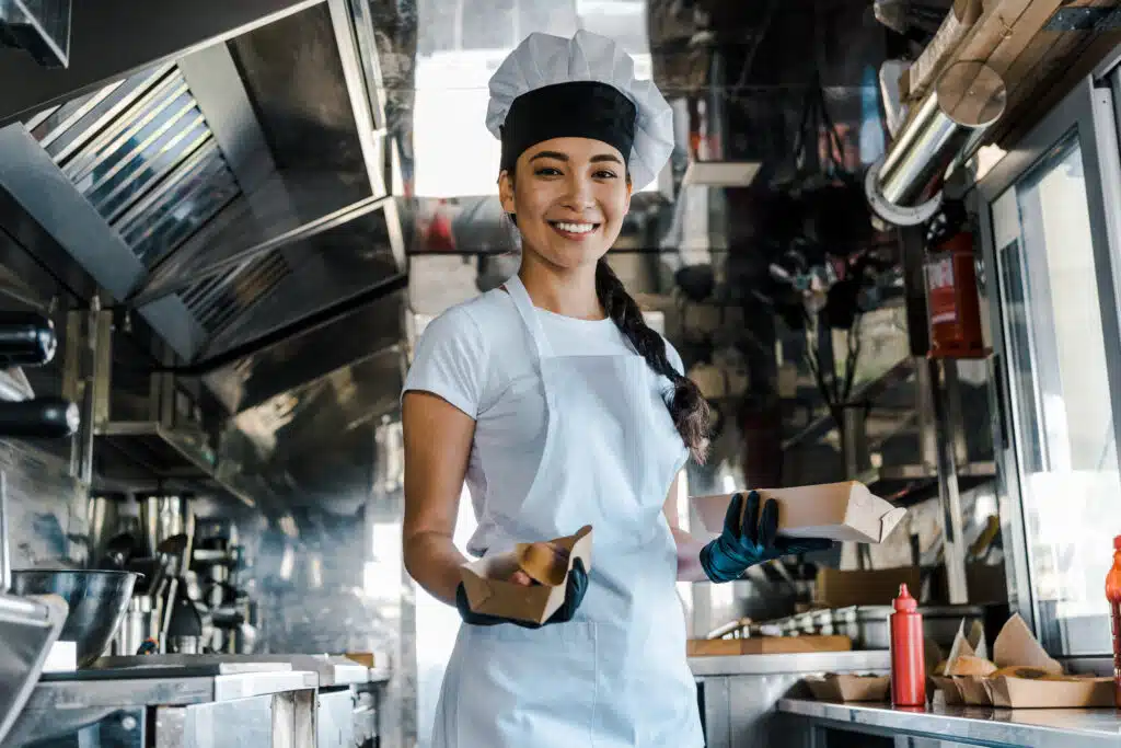 small food truck owner holding hot dog sandwich and smiling 