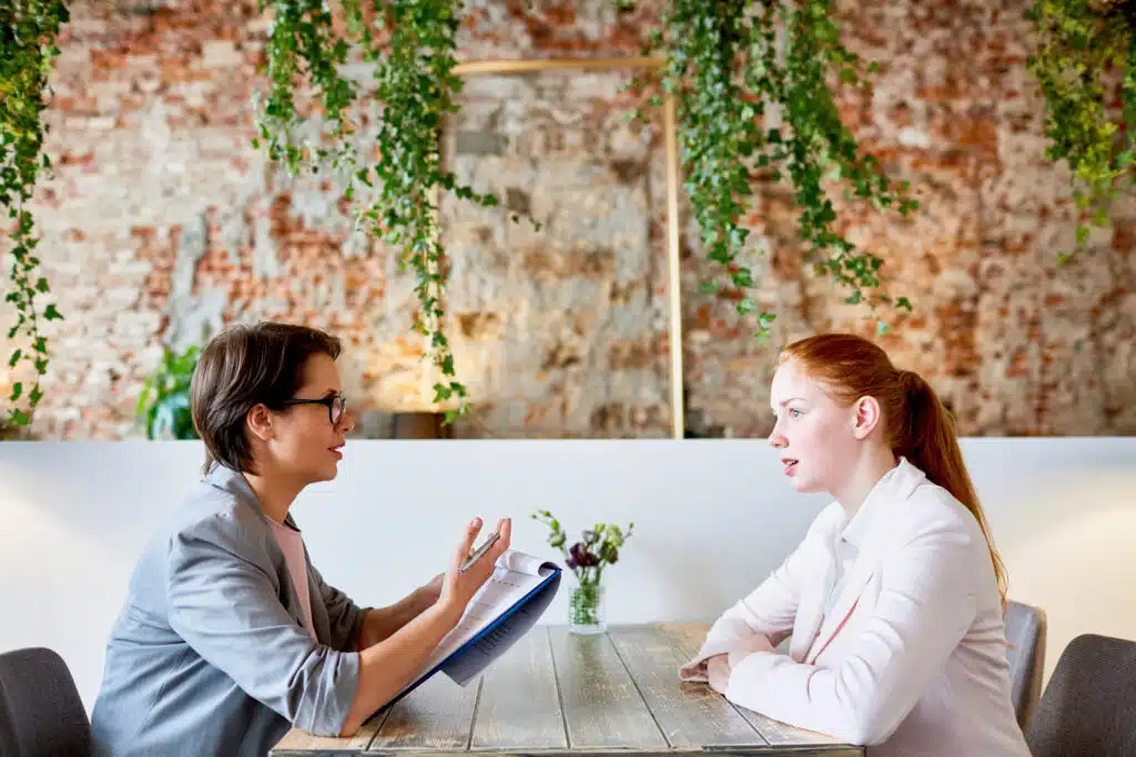 small business owner conducting job interview with young female professional in person