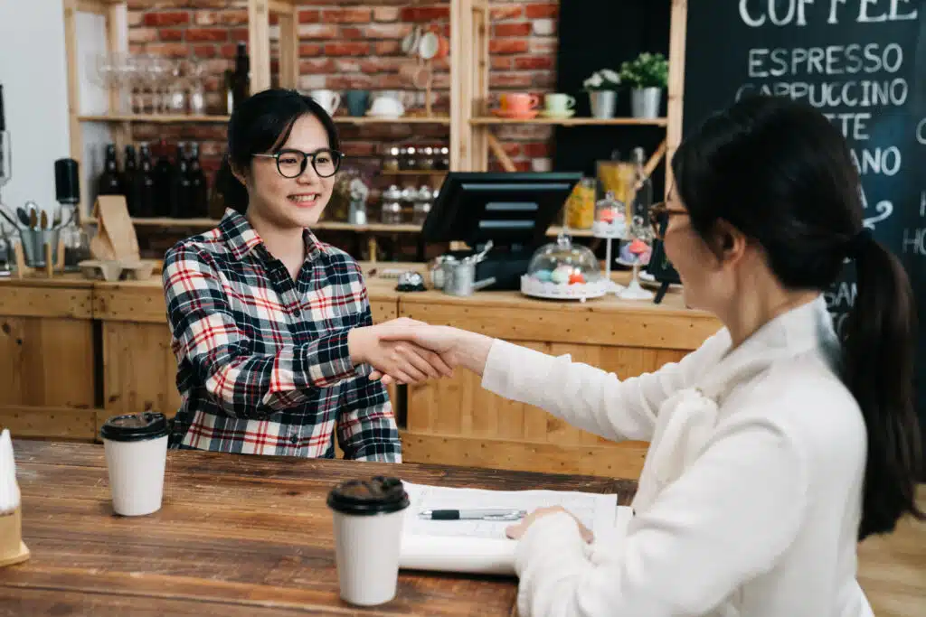 small caffe owner making job offer for young professional while shaking hands