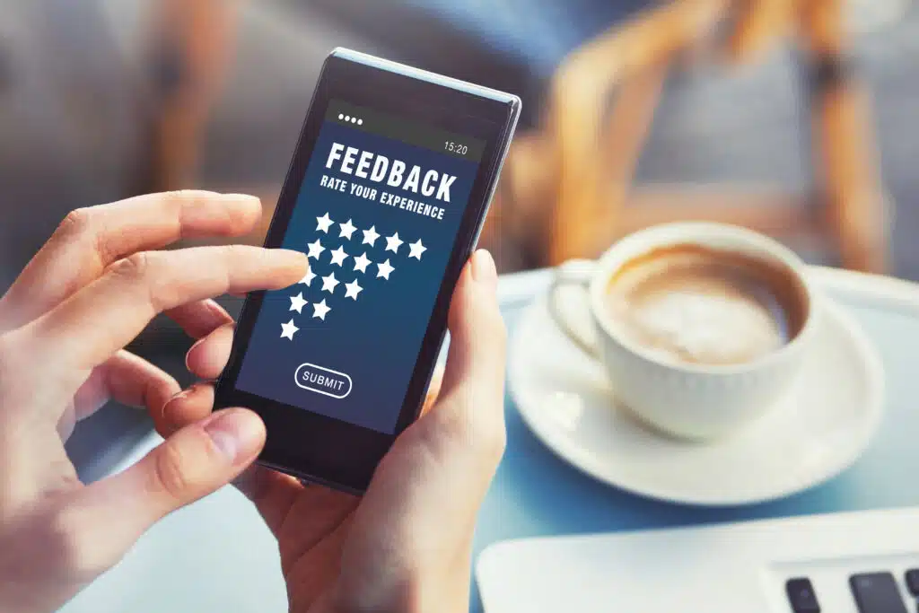 phone showing feedback ratings stars options in a cafe setting