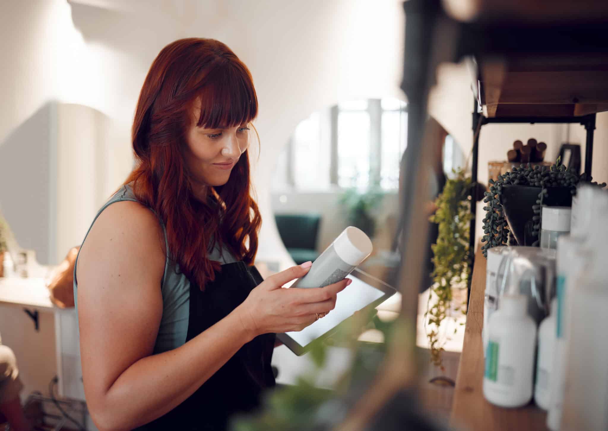 salon owner controlling inventory of products with tablet in one hand