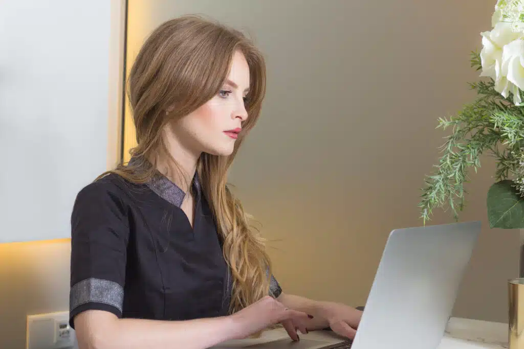 spa receptionist using laptop to book a consultation