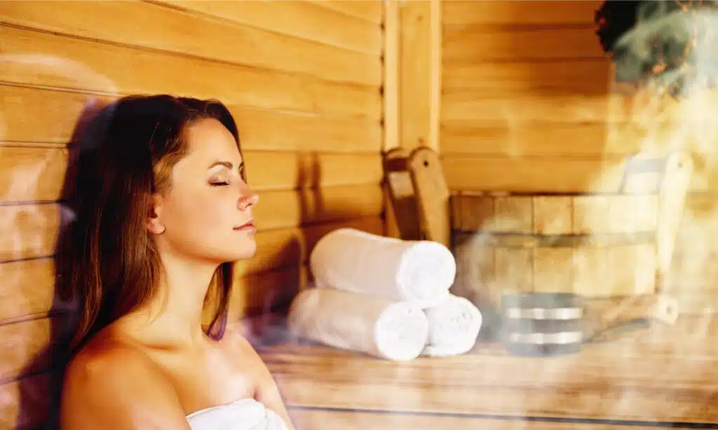 young woman in sauna with eyes closed